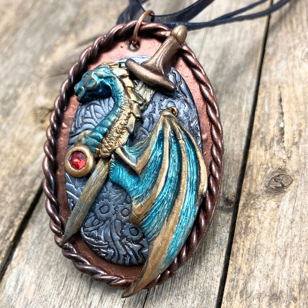 Handmade fantasy dragon and sword pendant necklace in green, bronze, and red tones. High fantasy jewelry gift for dragon lovers and cosplay fans.