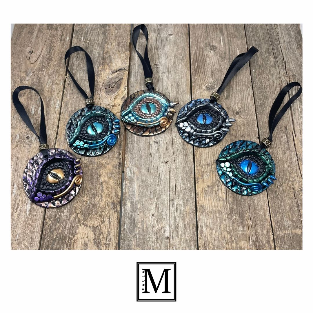 A collection of round dragon eye ornaments with black satin ribbonsaligned in a semi-circle in bright metallic colors