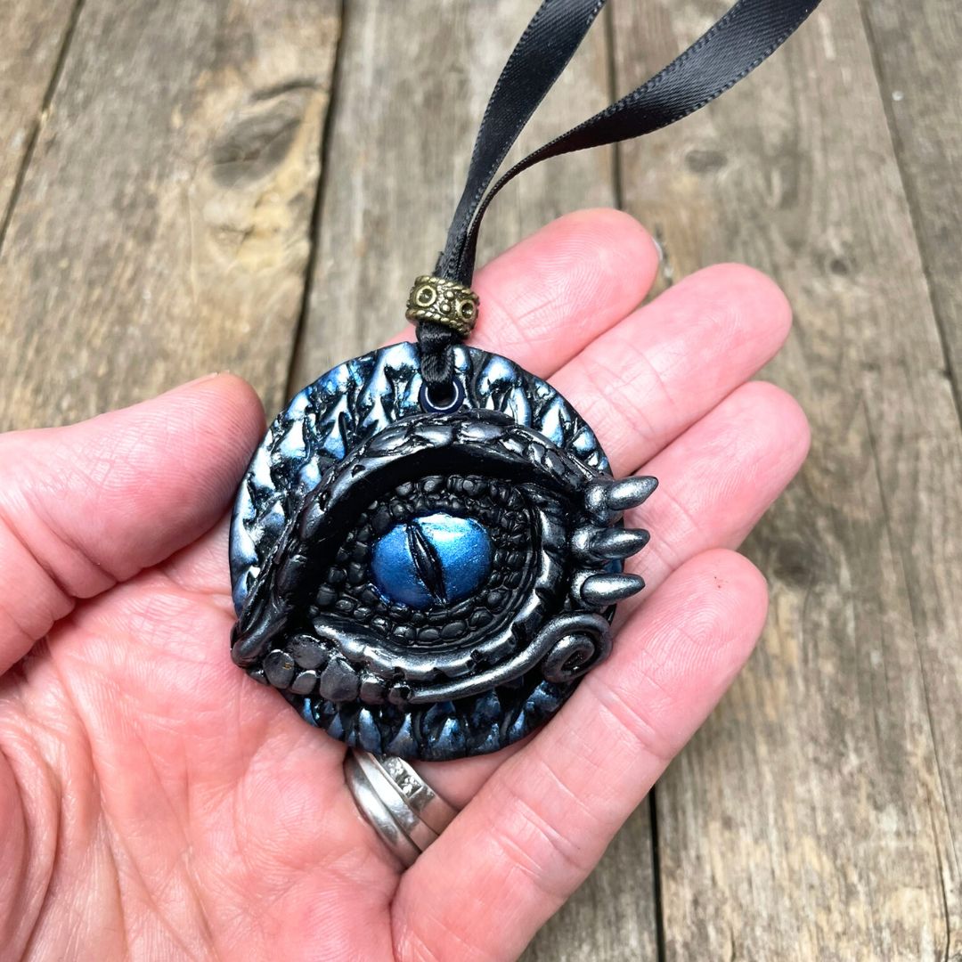 Decorative eye-shaped ornament held in a hand on a wooden surface