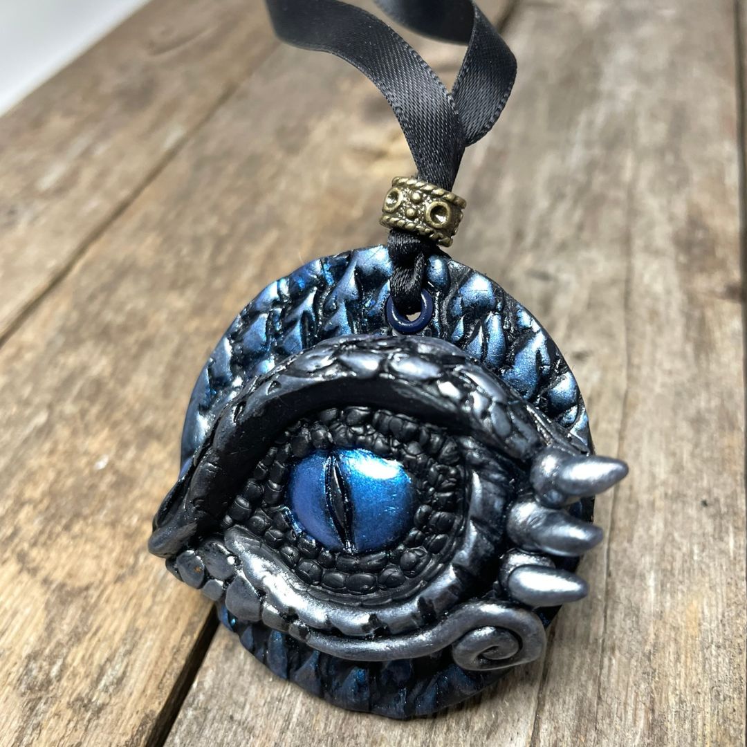 Decorative pendant with blue eye design on a wooden surface