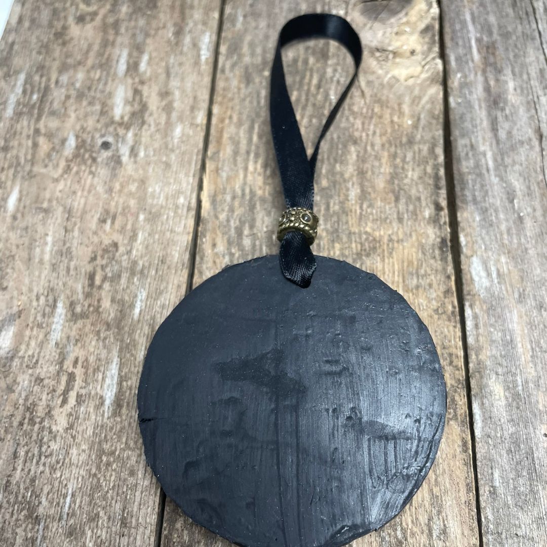 back of dragon ornament with a ribbon on a wood surface.