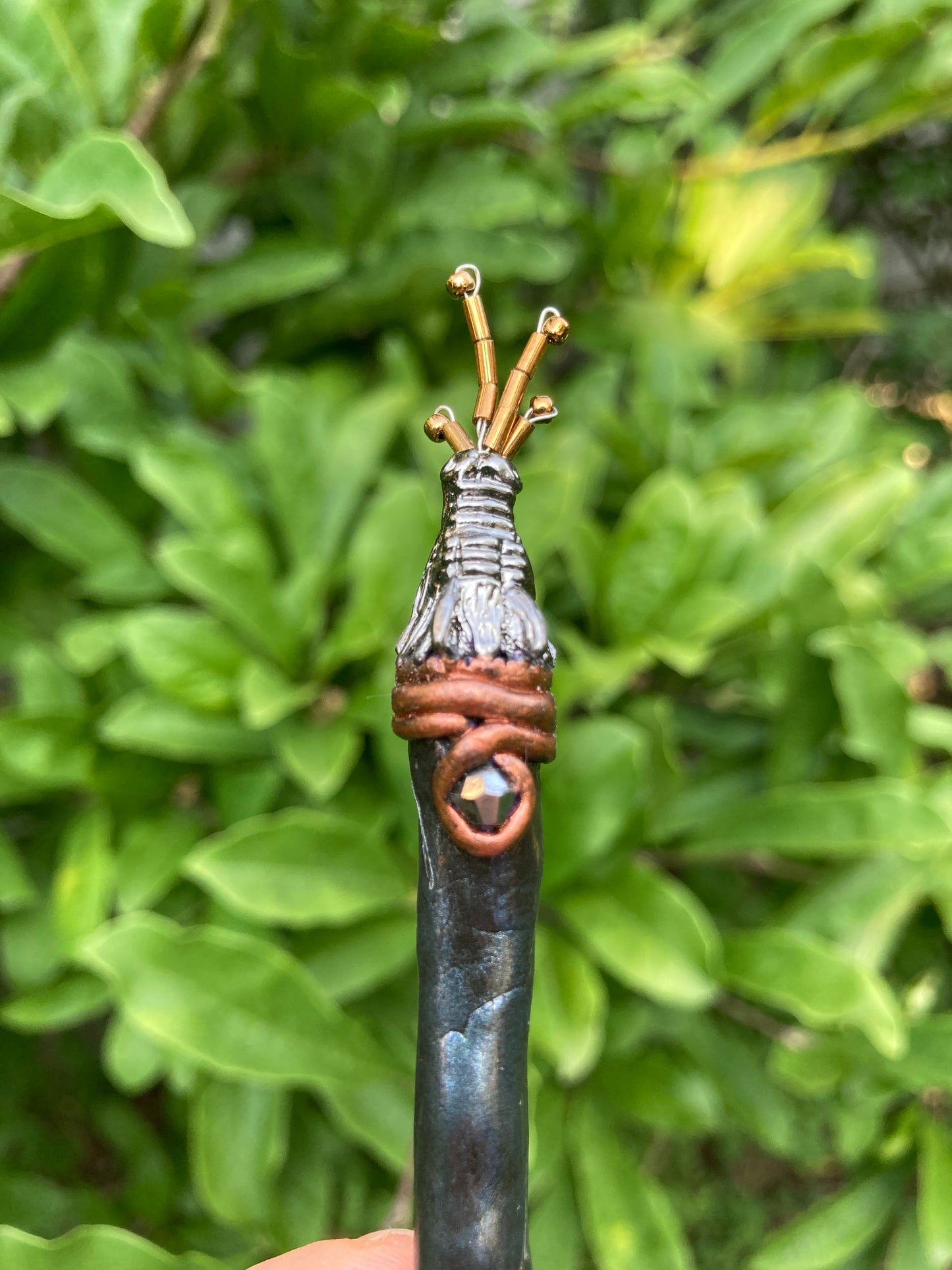 dragon hair pin  held vertically in a hand with dragon head breathing fire made from  gold seed beads.