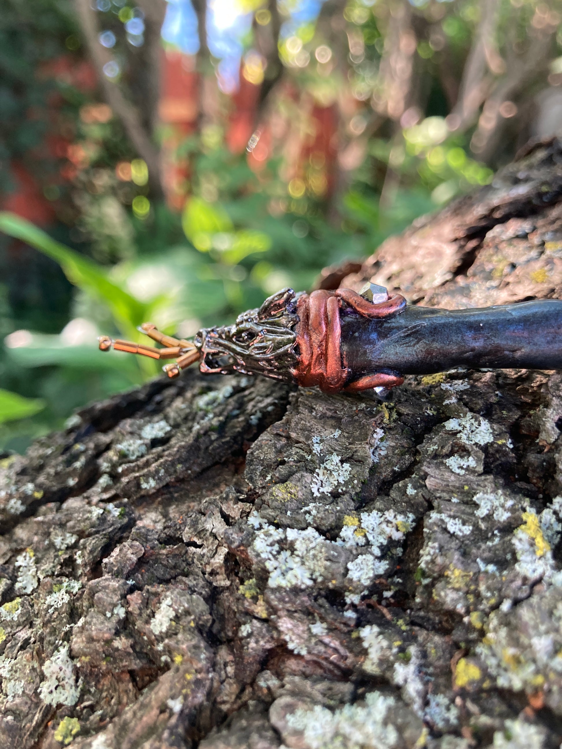 A close up of a the dragon head hair stick laying on a tree branch
