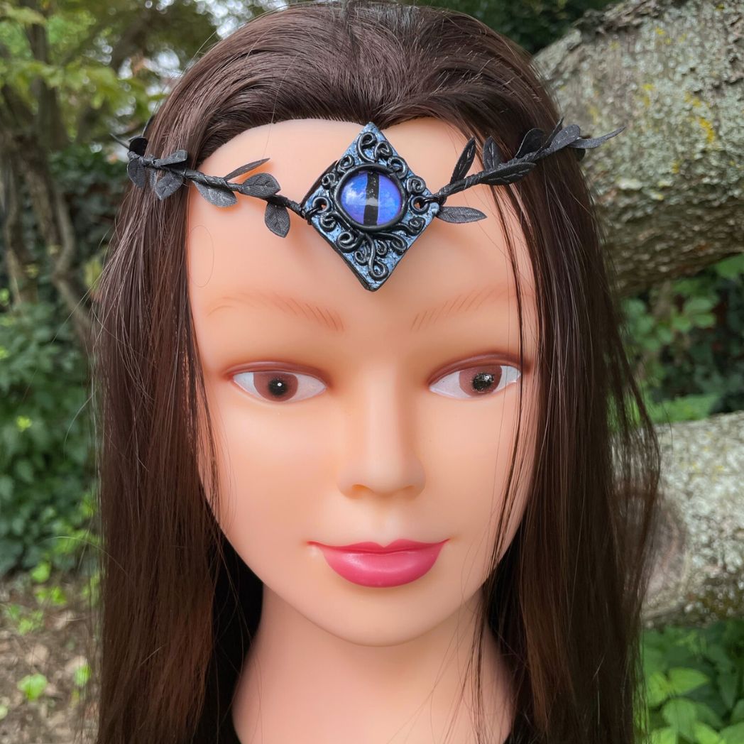 Purple dragon on a diamond shape textured clay base on a black leaf wire headband on a model.