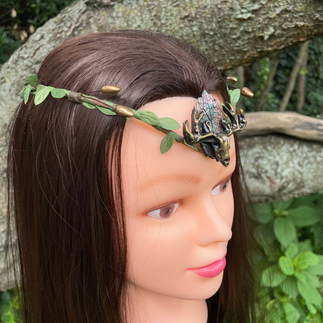 A wire crown with green leaves and a polymer clay leaf and elk focal on a model.