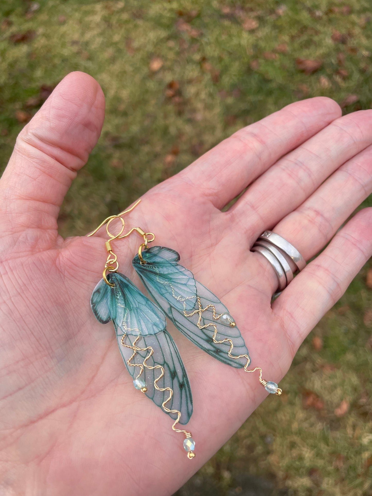 forest fairy wing earrings with gold accents held in hand