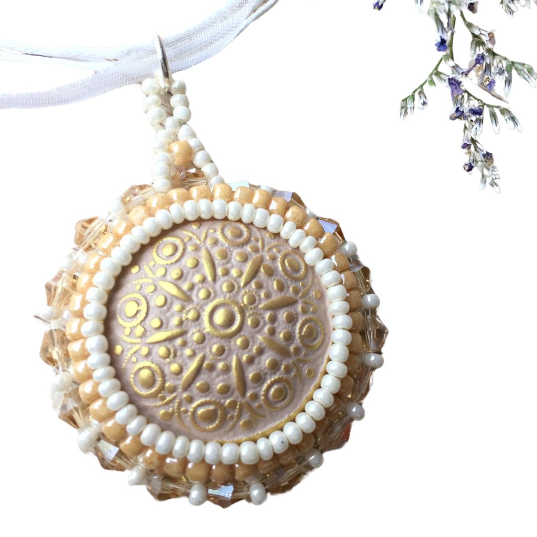 A golden beaded necklace with topaz crystals on a white cord necklace on a white background with flower in top right corner.