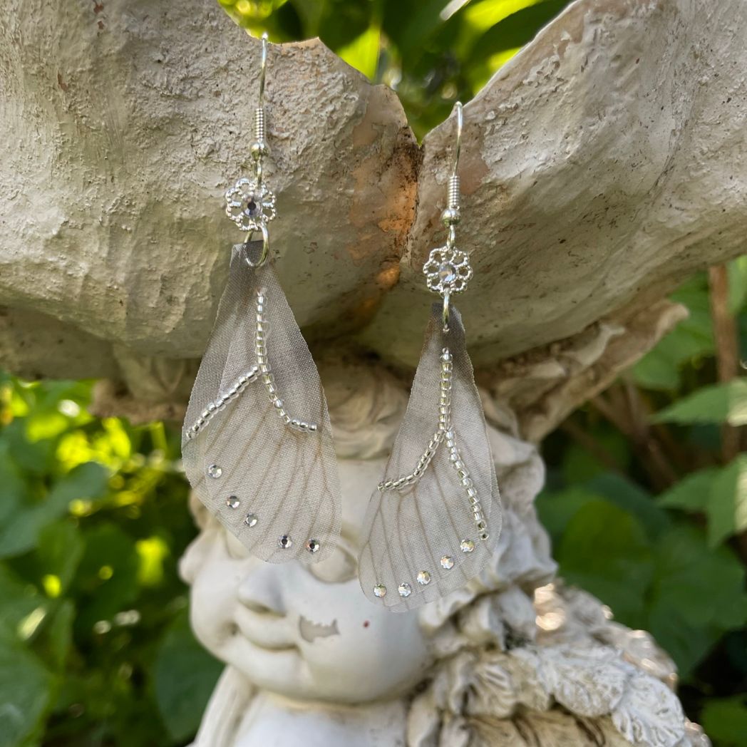 Silver beaded gray sheer fabric butterfly wing earrings with crystals and a flower bead connecting to the ear wires.