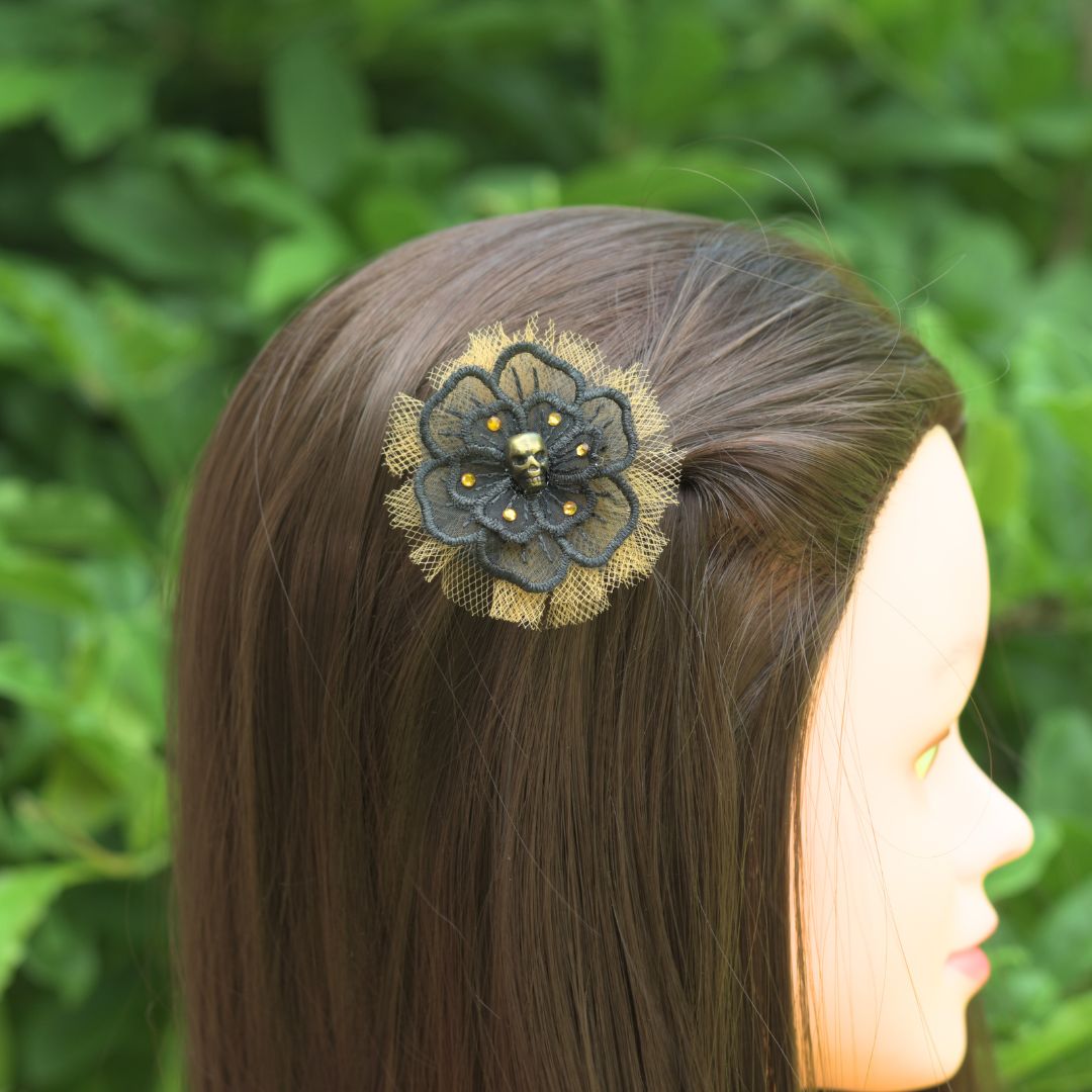 Black flower applique with a gold skull in the center surrounded by orange crystals and orange tulle behind the black flower on a model.