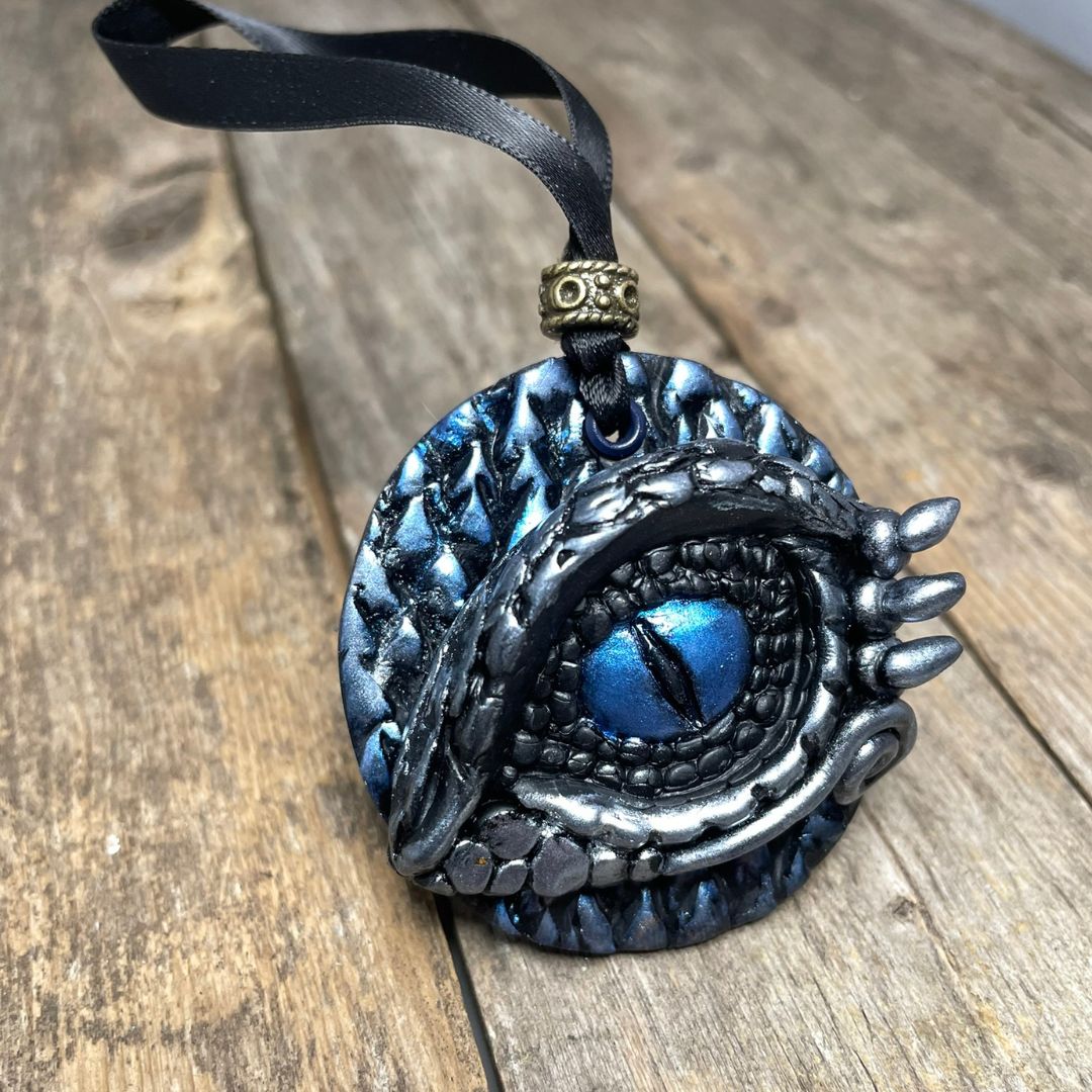 A round dragon eye ornament with metallic silver and blue coloring with black satin ribbon 