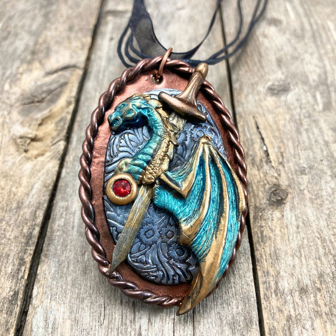 Handmade fantasy dragon and sword pendant necklace in teal, bronze, and bronze tones. High fantasy jewelry gift for dragon lovers and cosplay fans.