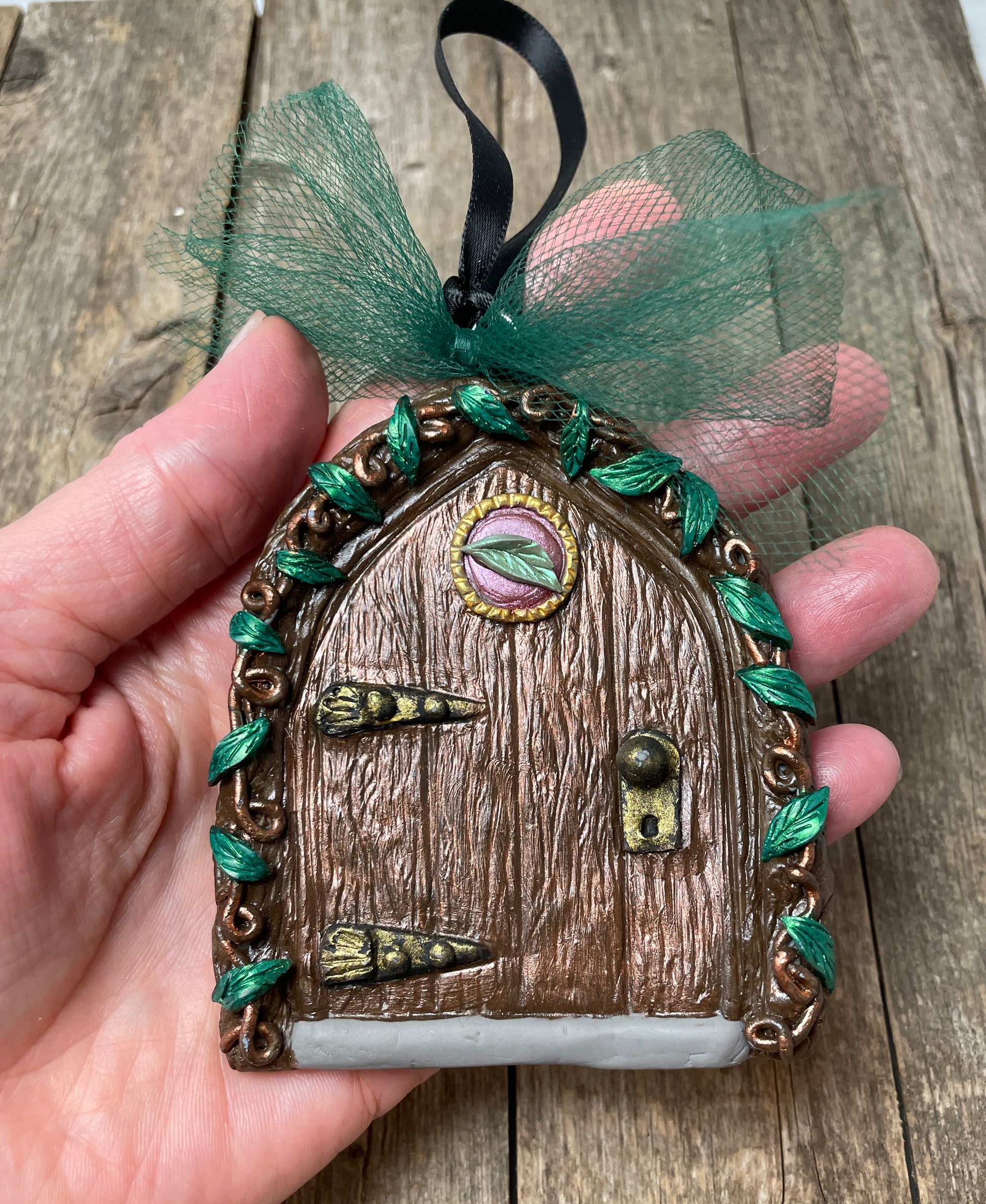 fairy elf door ornament with green tule bow held in a hand