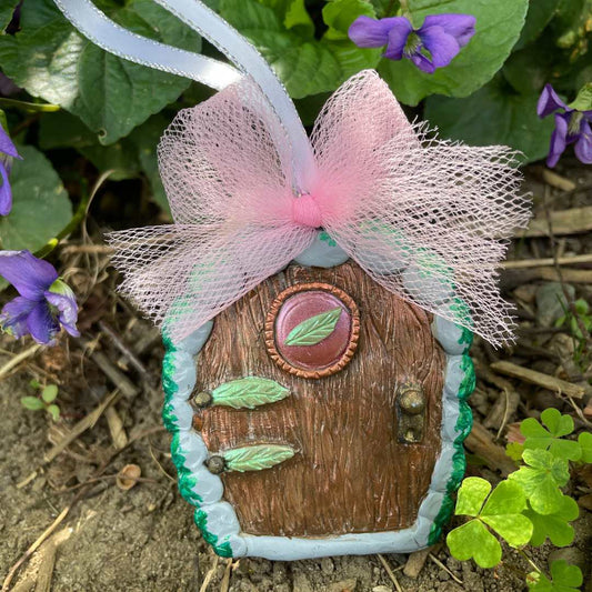 Elven fairy door ornament with leaf motif and pink tulle bow in a garden setting.