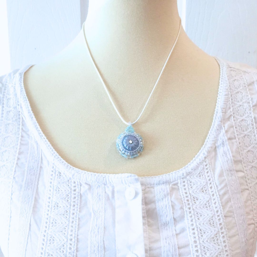 light blue flower necklace on a model against a white background.