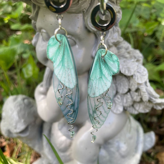 green butterfly jewelry ear gauges hanging from a garden ornament