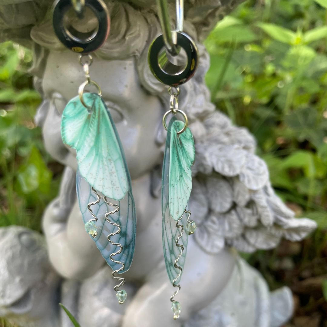 green buttefly ear gauge earrings on a garden ornament