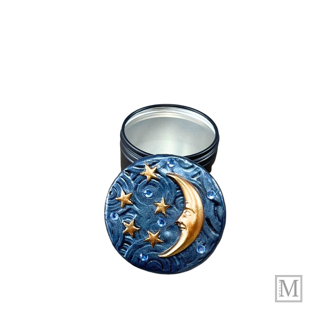 4oz candle tin with deocrative lid. Lid is blue textured polymer clay with gold crescent moon, stars an blue crystals.