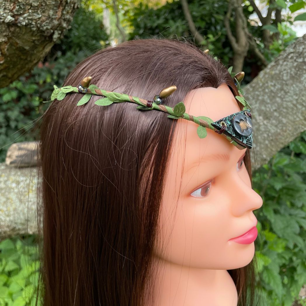 Silver and green triple moon focal on a brown wire and green leaf crown resting on a branch.