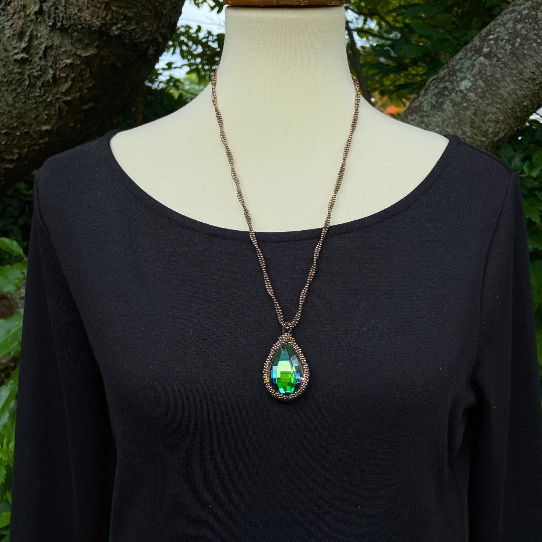 large pear shaped rainbow crystal necklace with twisted beaded chain on a mannequin