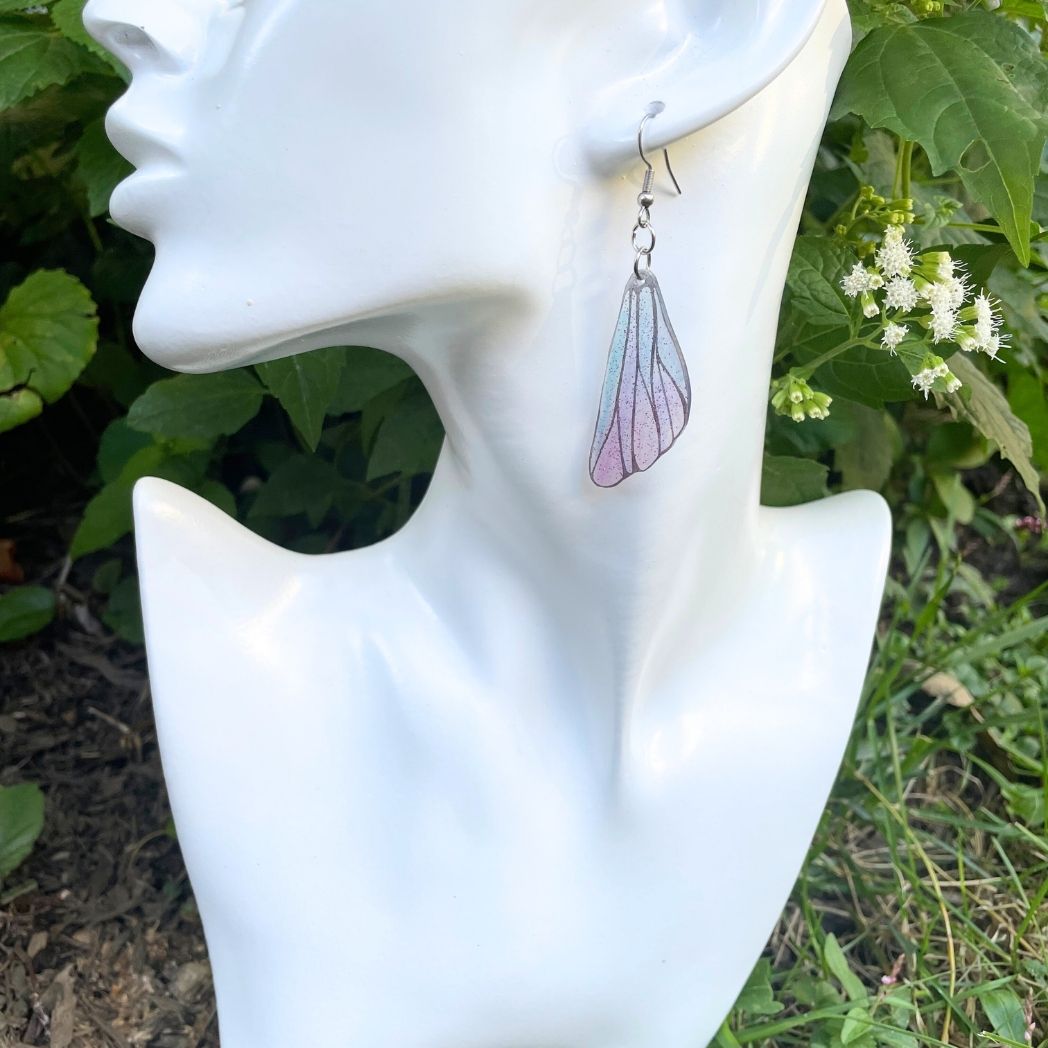 pink and blue wing earrings on an earring model bust.