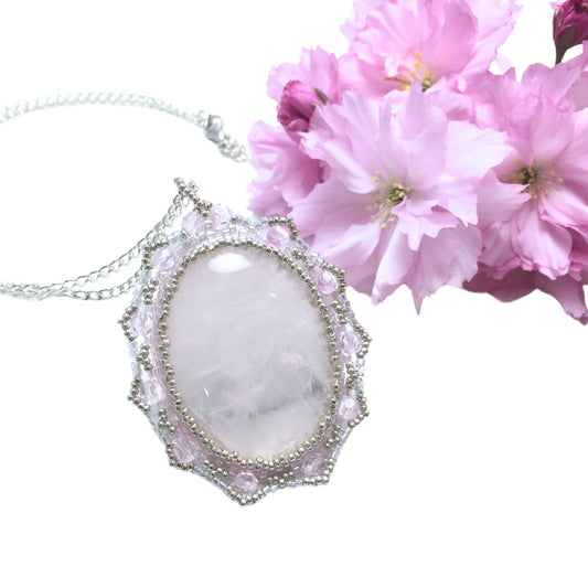 rose quartz beaded necklace with pink blossoms against a white background.