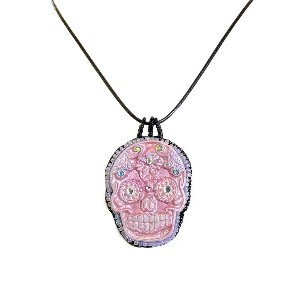 pink sugar skull necklace with colorful crystal details with seed beaded edging and black cord necklace.