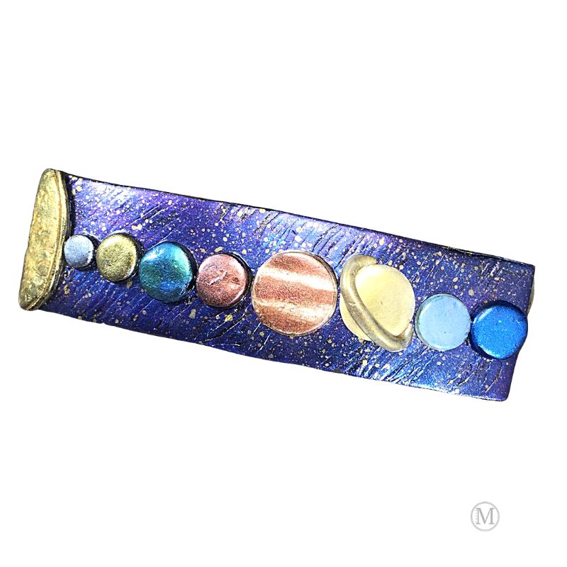 Handmade polymer clay hair barrette with purple/blue base with gold stars and hand painted solar system in clay represented in a line from the sun on far left.