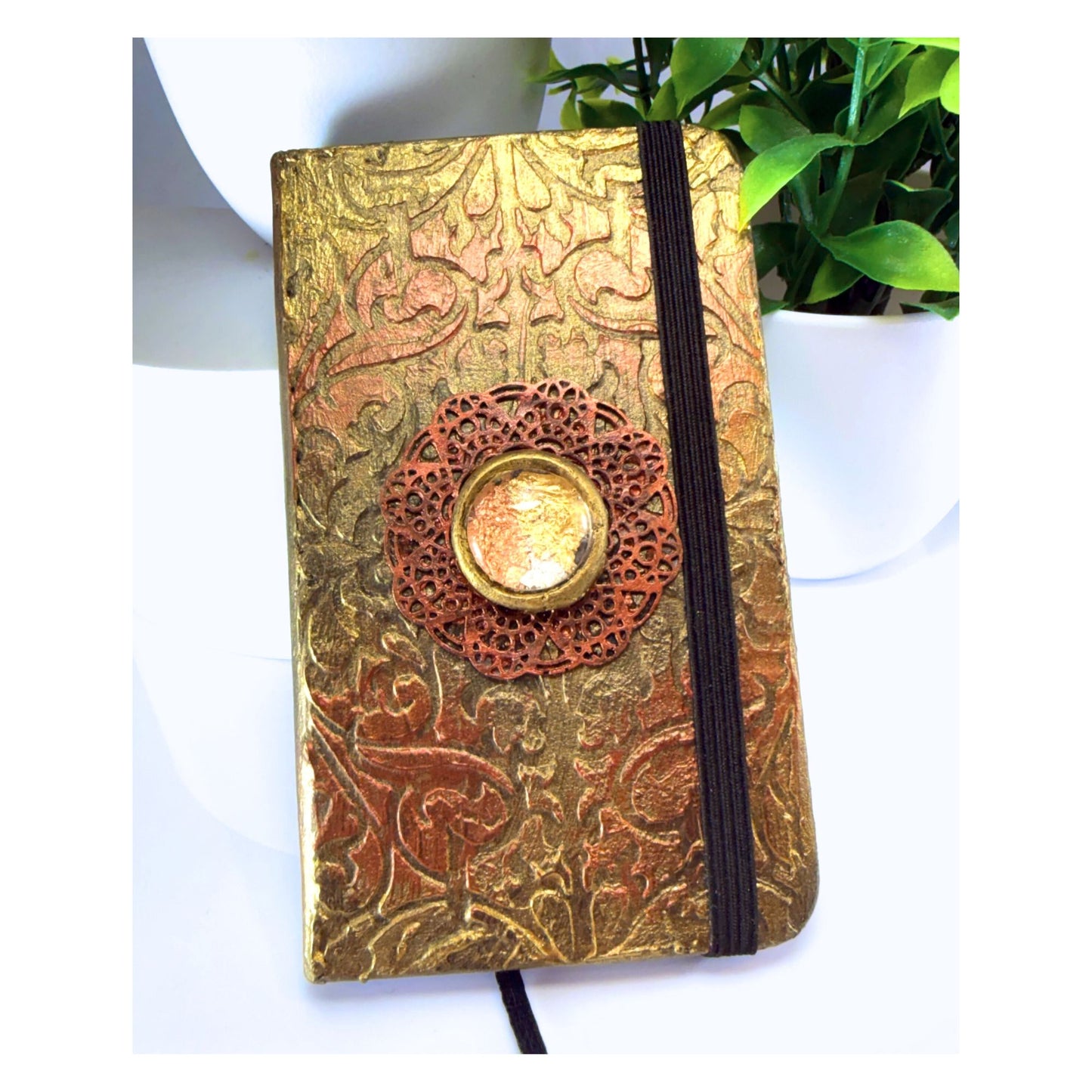 Decorative notebook with gold embossed cover and central button on a white background