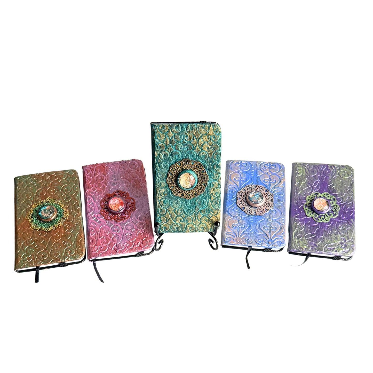 Five colorful metallic textured journals with decorative elements on a white background