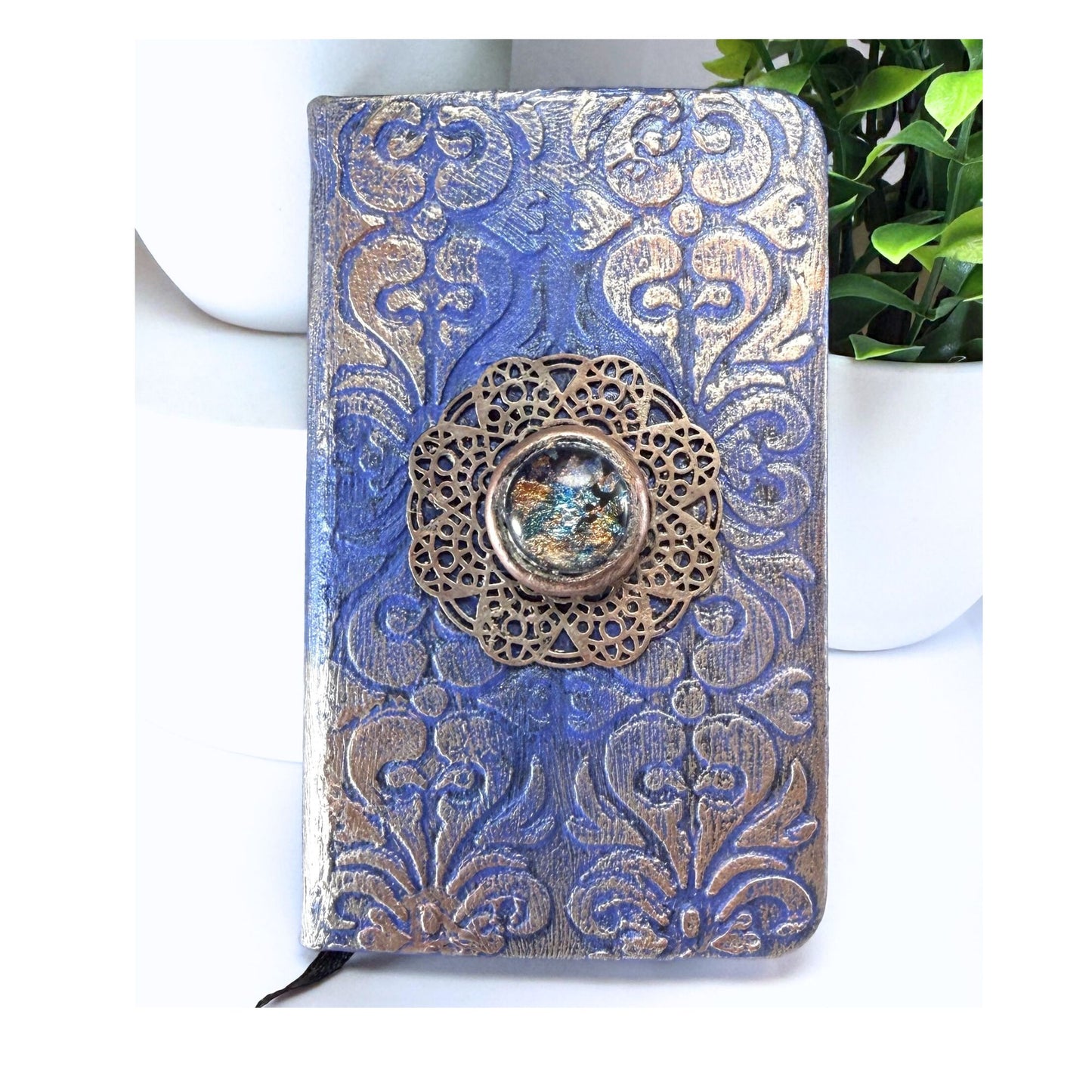 Decorative notebook with blue and gold pattern and a decorative button on a white background
