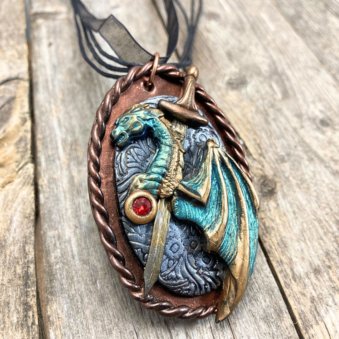 Handmade fantasy dragon and sword pendant necklace in teal, bronze, and red tones. High fantasy jewelry gift for dragon lovers and cosplay fans.