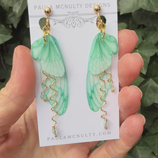 Mint green clip-on butterfly wing earrings with silver finish and comfort pads displayed on white background.
