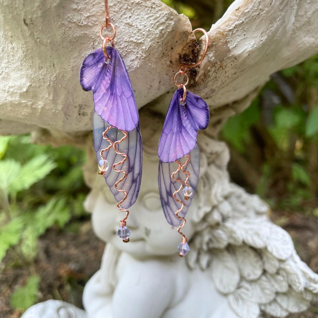 Violet  butterfly wing earrings with lavender crystals and copper wires. Hanging from fairy garden ornament.