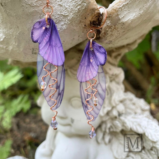 Violet purple fairy wing earrings with lavender crystals and copper wires. Hanging from fairy garden ornament.