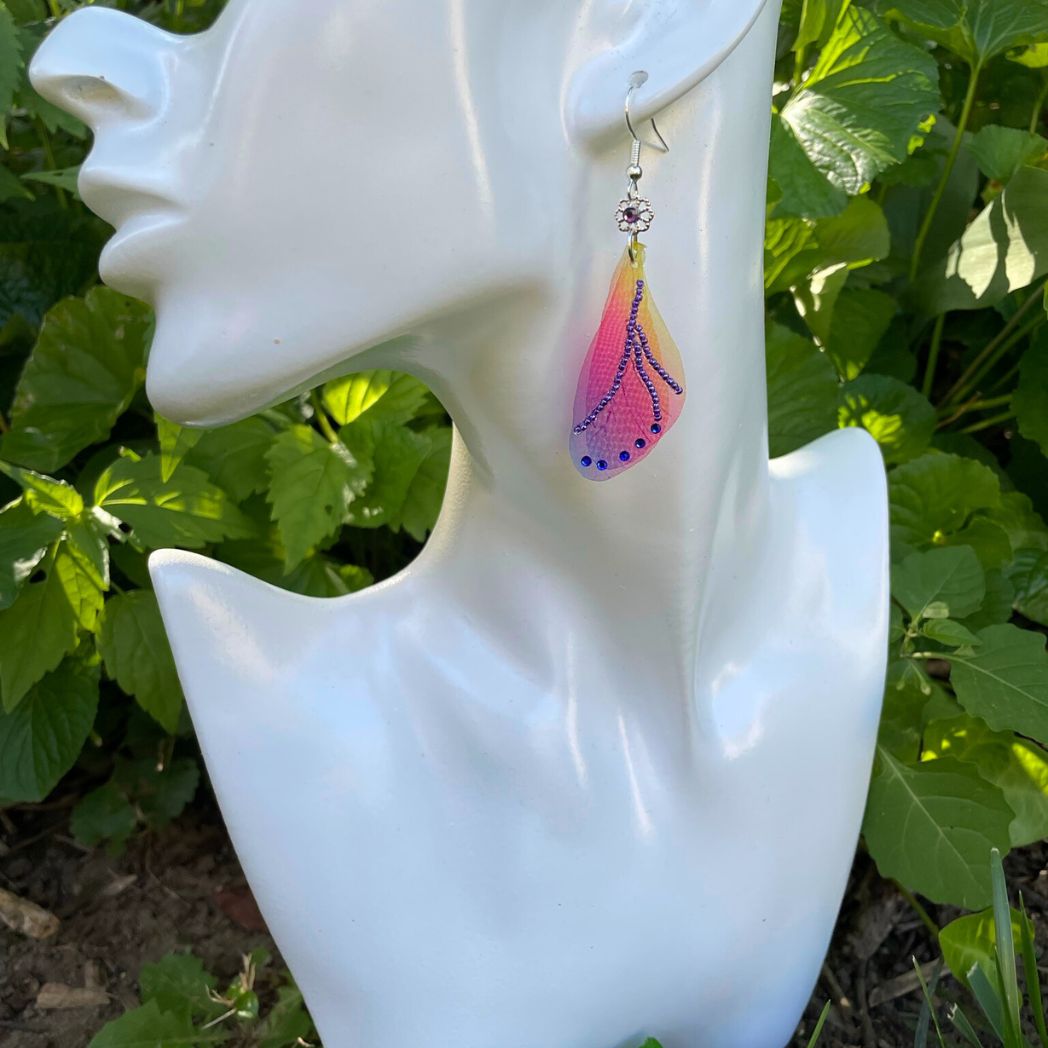 Colorful rainbow sheer fabric with beading and blue crystals. A flower bead with a crystal connects the wings to the ear wires. Displayed on a model bust.