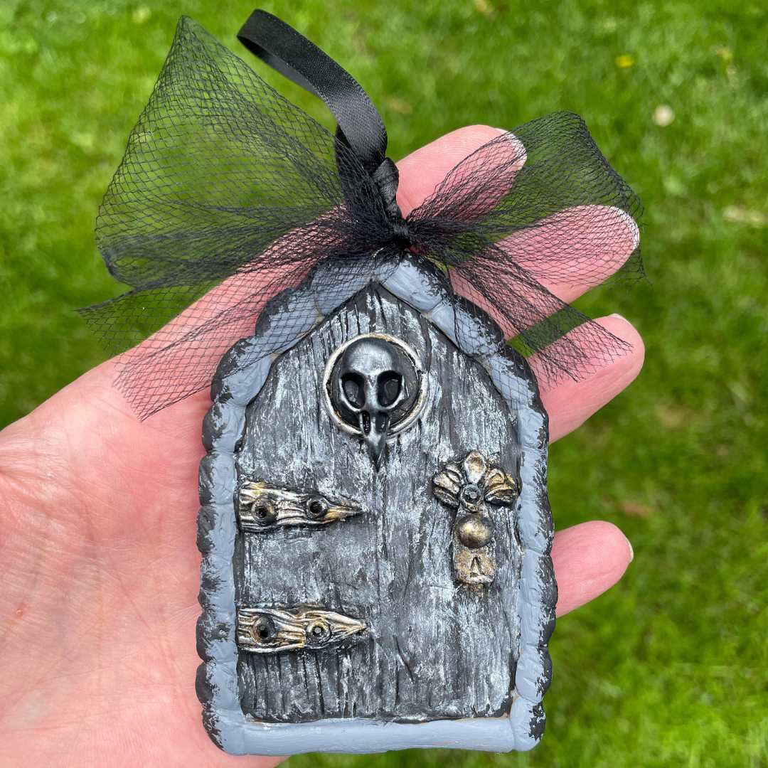 Dark fairy fairy door with raven skull motif, silver door and black tulle bow.