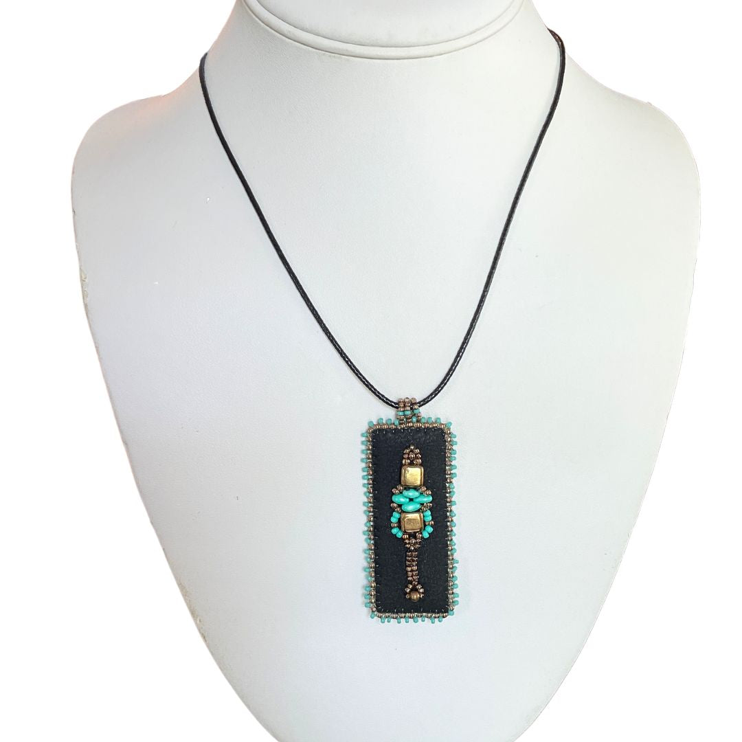 Medieval Jewelry black faux leather bar pendant with turquoise and gold beading with black cord necklace on a bust.