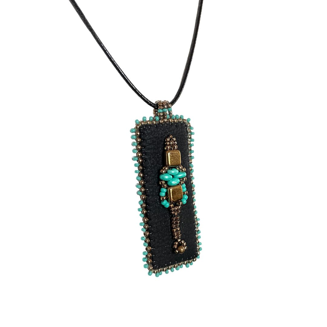 Medieval Jewelry black faux leather rectangle pendant with turquoise and gold beading with black cord necklace.
