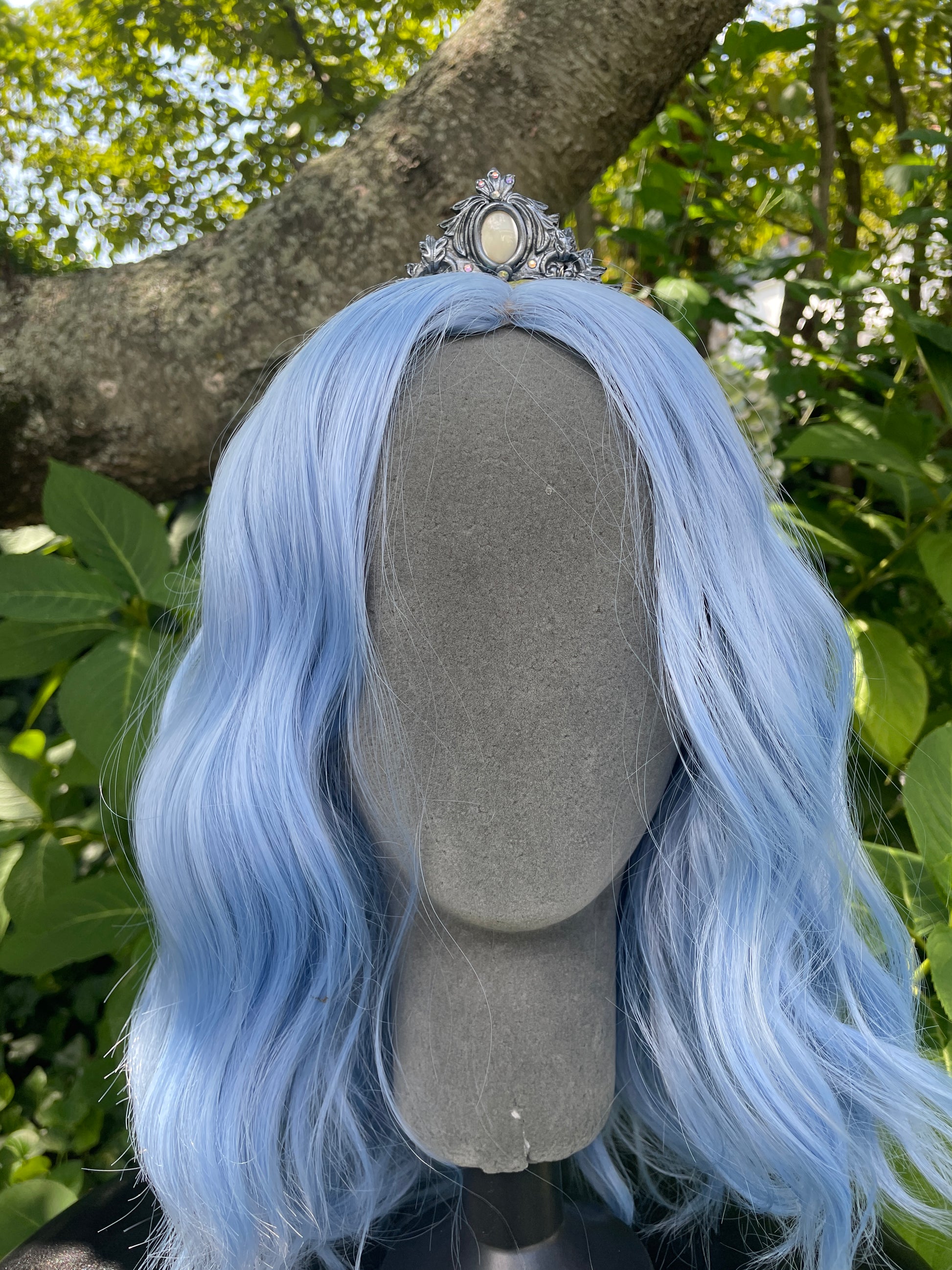 Silver mother of pearl mermaid crown on a model with blue hair in a garden

