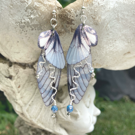silver double wing fairy earrings with silver twisted wired branches with crystals hanging from a garden ornament