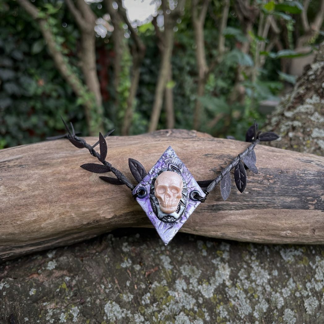 Skull  black leaf wire crown resting on a tree branch.