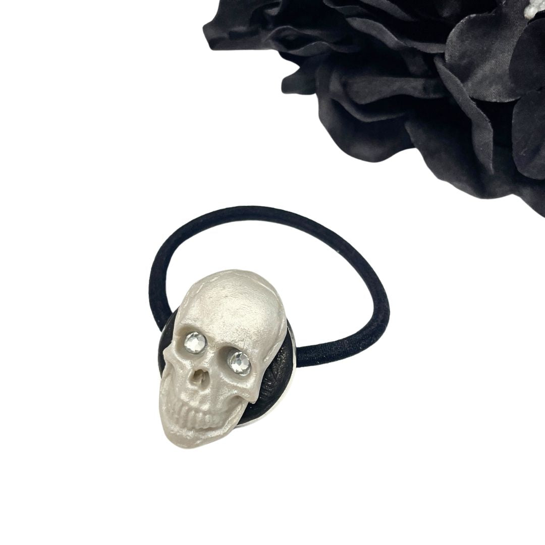 Left profile of Decorative Hair tie with polymer clay Skull with crystal eyes on a white background with black hydrangeas