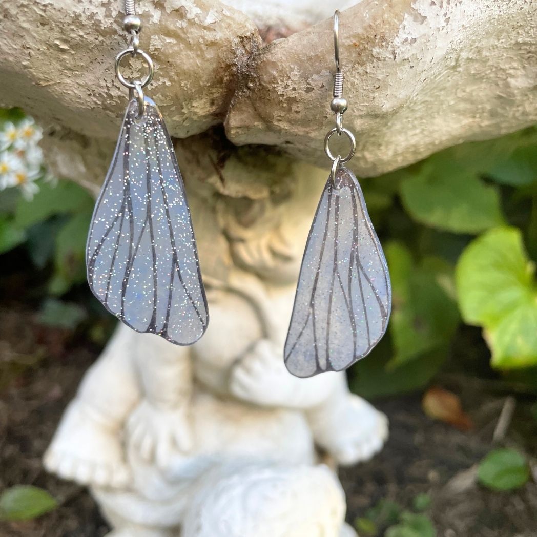 gray small wing earrings hanging on a garden ornment.