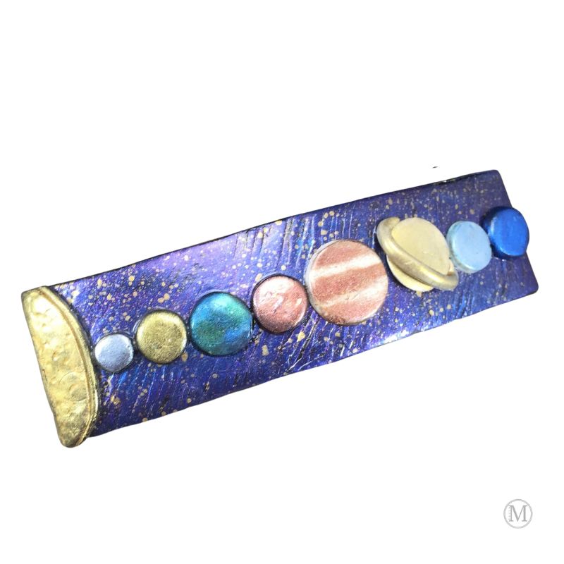 Handmade polymer clay hair barrette with purple/blue base with gold stars and hand painted solar system in clay represented in a line from the sun on far left.