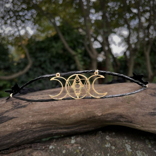 gold Triple moon motif on a black wire crown sitting on a tree branch.