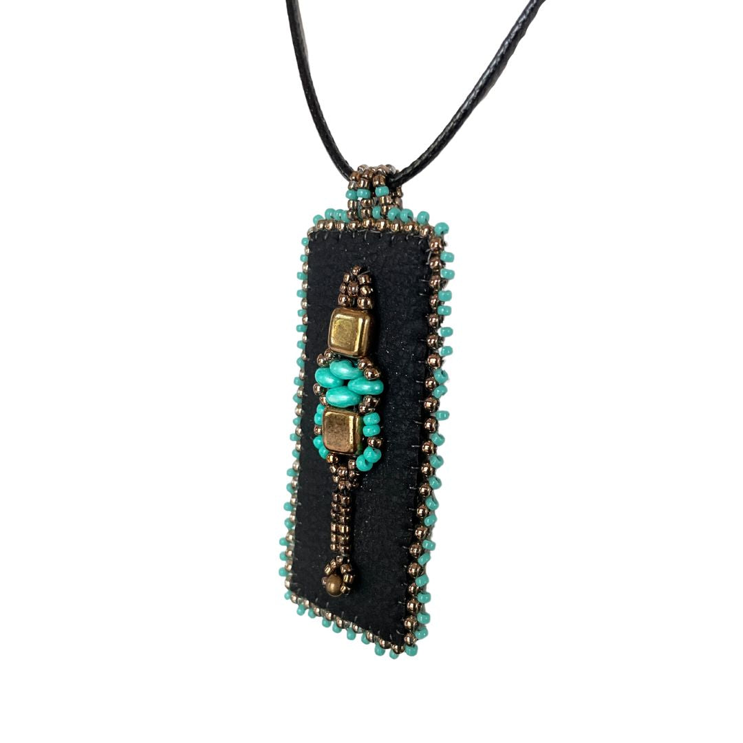 Medieval Jewelry black faux leather rectangle pendant with turquoise and gold beading with black cord necklace.