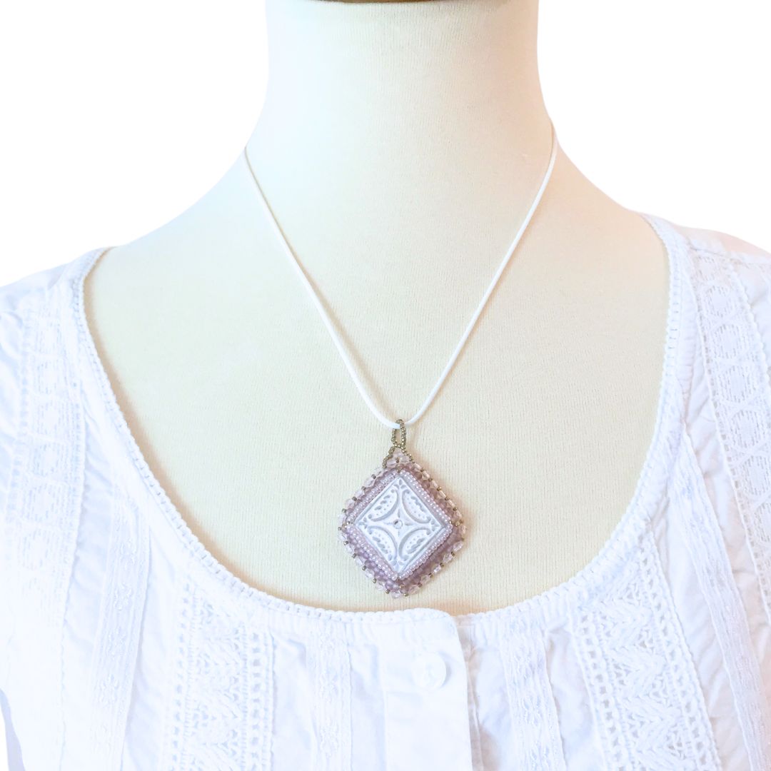 lilac beaded diamond shaped necklace on a model against a white background.