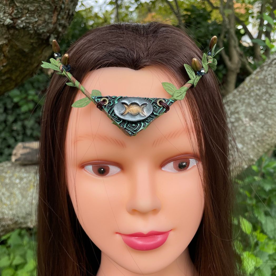 Silver and green triple moon focal on a brown wire and green leaf crown resting on a  model.