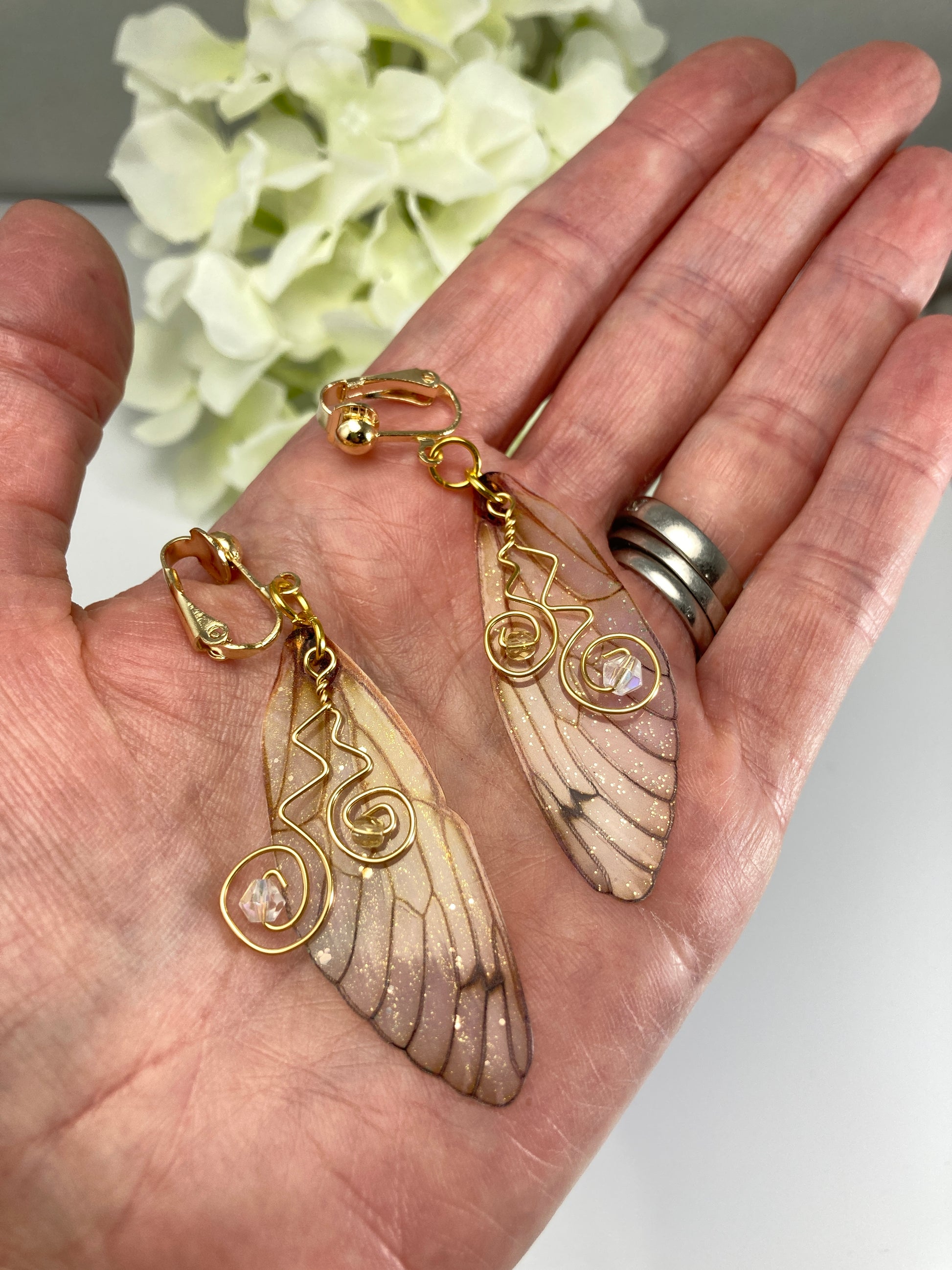 yellow butterfly wing clip on earrings displayed in a hand