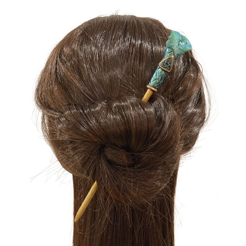 Green and gold hair stick with triquetra symbol and green druzy stone in mannequin's hair